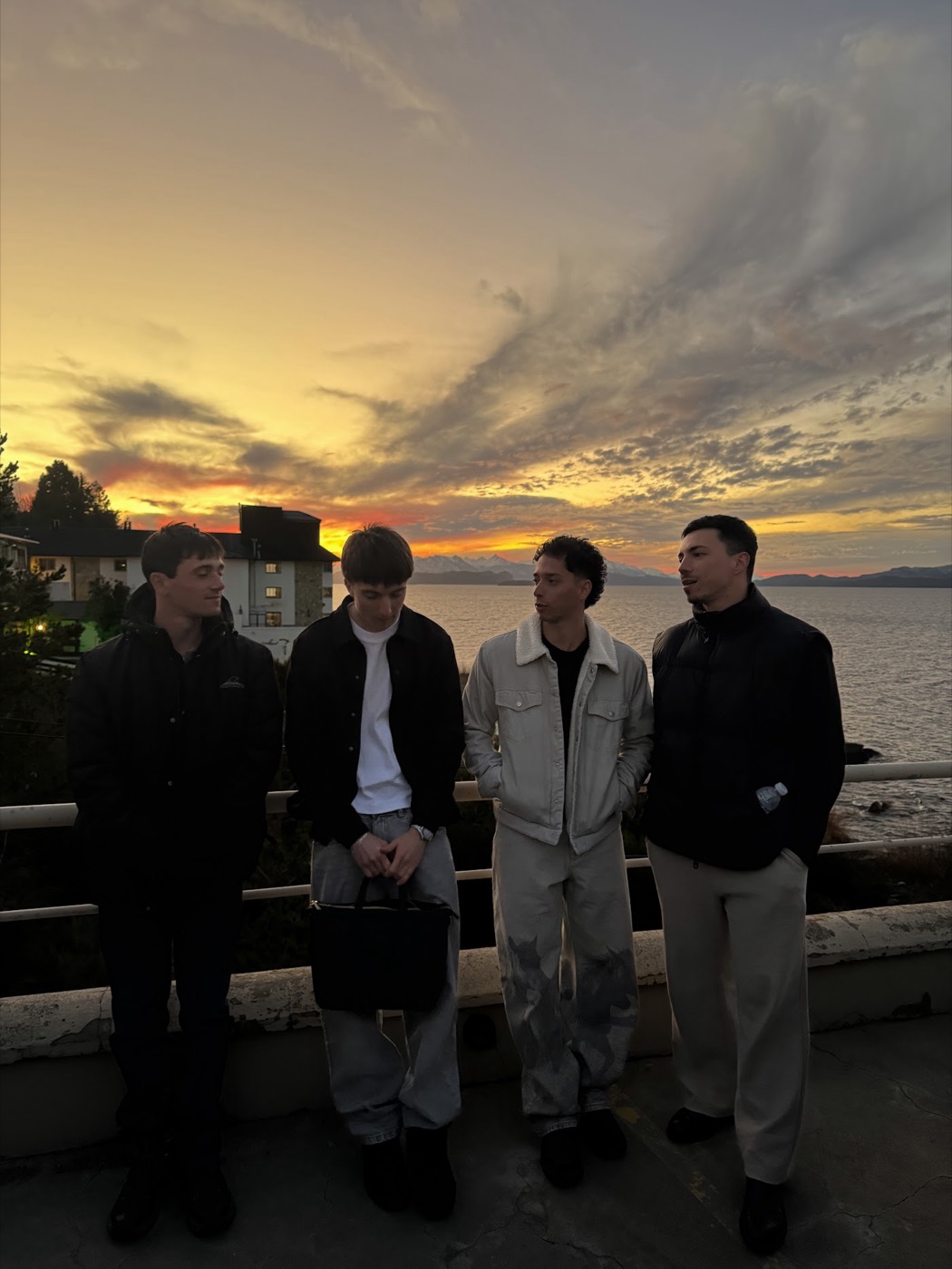 Cuatro participantes en un balcón frente al lago al atardecer