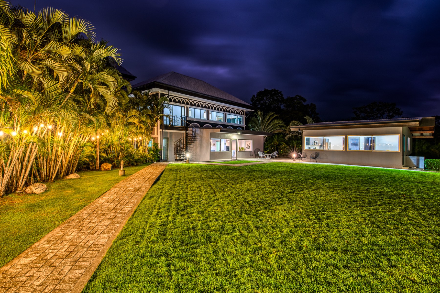 Jardín y fachada de la casa iluminados de noche